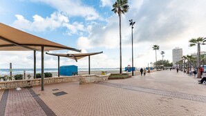 A paved promenade with a beach view, palm trees, and a covered seating area. - MalagaSuite Terrace&Parking Stay Fuengirola (Fuengirola)