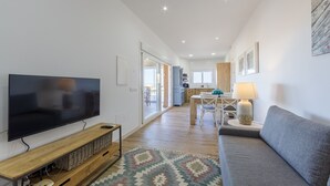 Un salon moderne doté d’un téléviseur à écran plat, d’un canapé gris, d’un meuble de rangement en bois et d’un tapis à motifs.