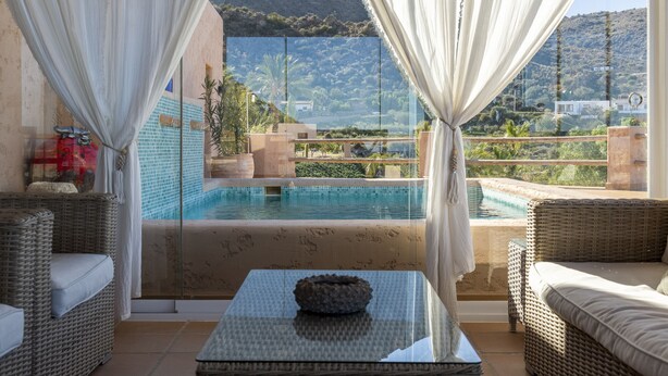 Une pièce dotée d’un mur de verre donnant sur une piscine et un paysage montagneux.