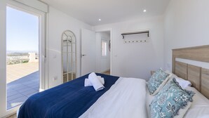 Une chambre à coucher avec un lit, une fenêtre et une porte donnant sur un balcon.