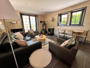 Uma sala de estar com sofá, poltronas, mesa de centro e lareira.