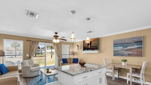 A spacious living area with a sofa, a dining table, and a kitchen island. - 1st Floor-Pool-Short, Easy Walk to Beach & Restaurants-Seacove 6A🌊 (MIRAMAR BEACH)