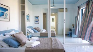Et hotelværelse med en stor seng, et spejl og havudsigt fra vinduet.