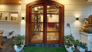 A wooden door with glass panels, a green artificial grass entrance, and potted plants. - The Paradise - Luxury 3BR Villa Near the Airport in Dehradun (Rishikesh)