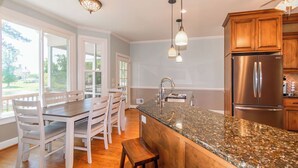 A modern kitchen with a granite countertop, stainless steel appliances, and wooden cabinets.