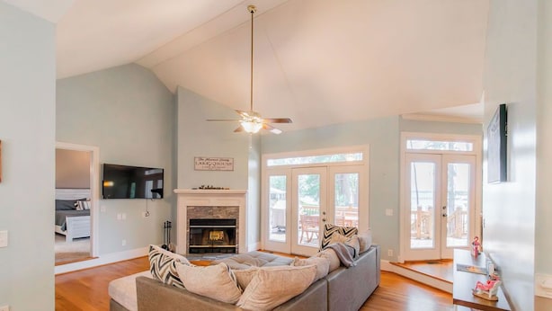 A spacious living room with a large sofa, a fireplace, and a ceiling fan.