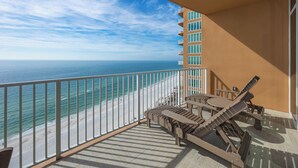 A balcony with a view of the ocean, a table, and two lounge chairs. - Brand New!! PGT 1807    Enjoy that Gulf Breeze (Orange Beach)