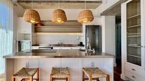 A modern kitchen with a central island, pendant lights, and built-in bar stools.