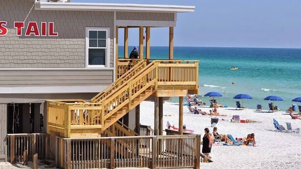 A beachside building with a wooden deck and a lifeguard tower.