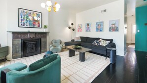 A living room with a fireplace, sofa, coffee table, and artwork on the wall.