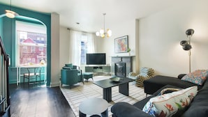 A modern living room with a sofa, coffee table, and chairs, a fireplace, and a television.