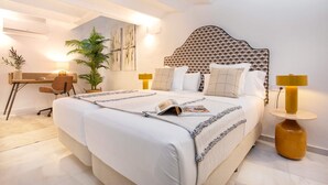 A bedroom with a large bed, a desk, a chair, a lamp, and a potted plant. - Genteel Home Gran Poder II (Seville)