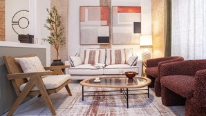 A modern living room with a white sofa, wooden armchairs, and a glass coffee table. - Genteel Home Gran Poder II (Seville)
