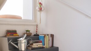 Eine Treppe mit einem Metall-Eimer, Büchern und einem hängenden Wandbehang aus Fransen.