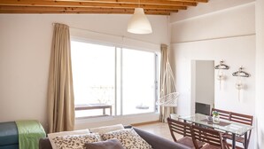 Ein gemütliches Wohnzimmer mit einer Couch, einem Esstisch und einem Hängesessel.