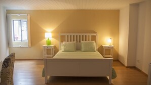 Ein Schlafzimmer mit einem Bett, zwei Nachttischen, einem Fenster und einer Decke mit Holzbalken.