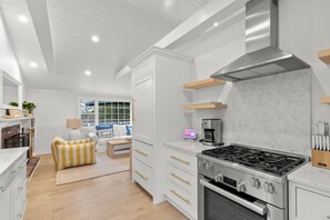 A modern kitchen with white cabinetry, a stainless steel range hood, and a built-in oven.