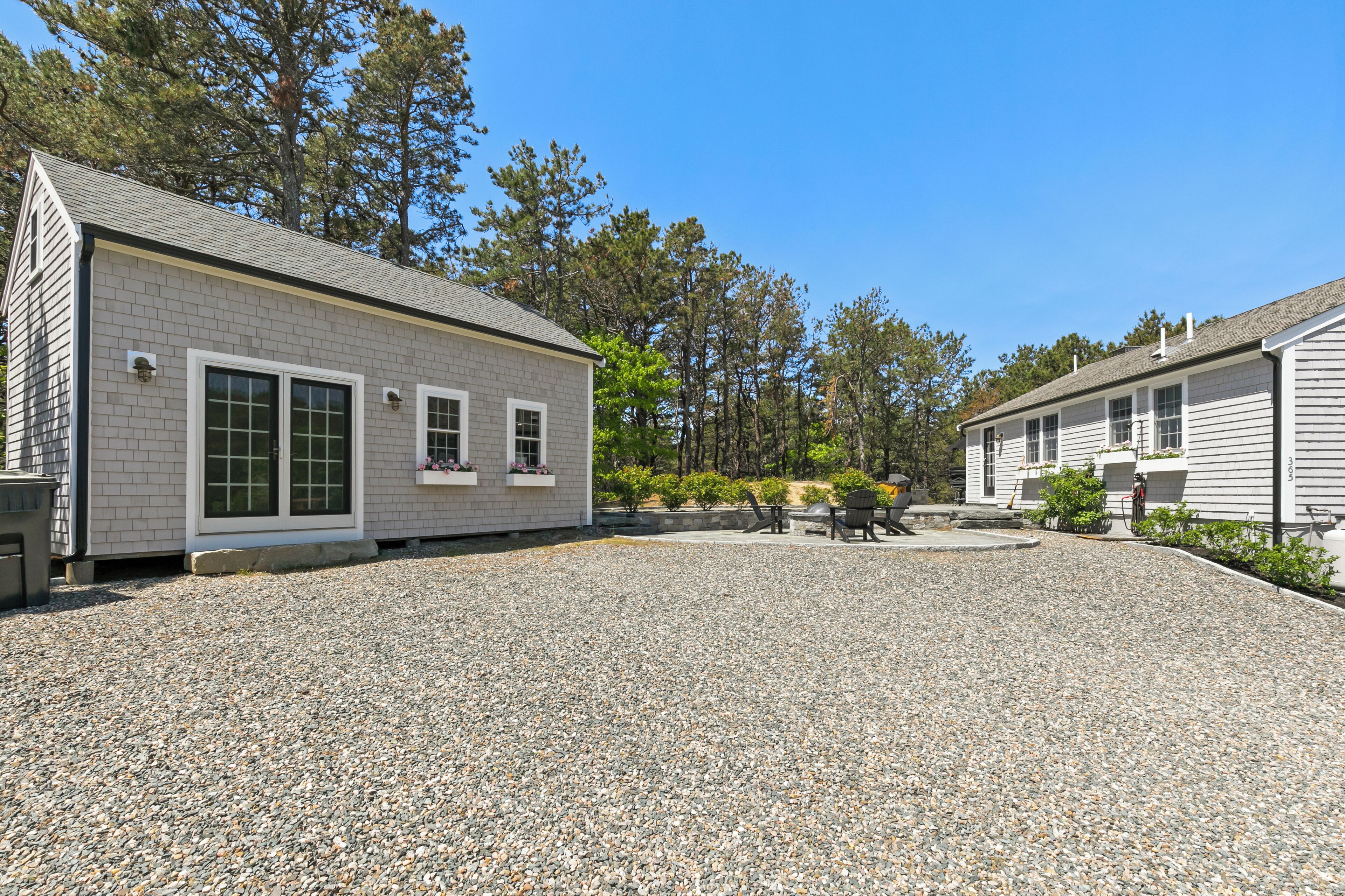 A two-story building with a gravel driveway, large windows, and a small patio area.