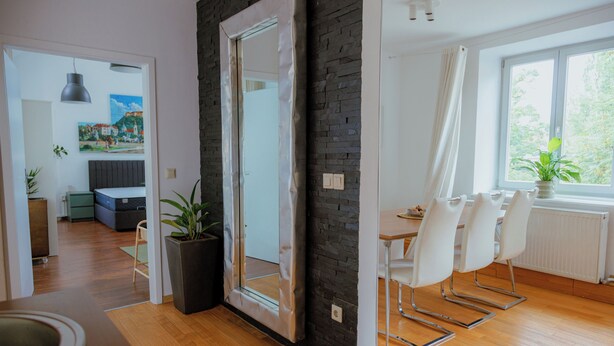 Un salon moderne comprenant un coin repas, un plancher en bois et une grande fenêtre agrémentée de rideaux.