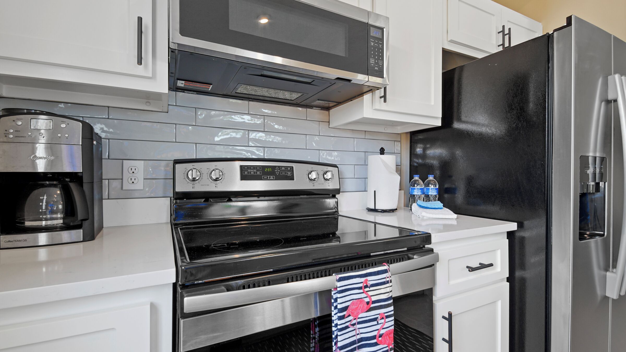 A modern kitchen with a black oven, stainless steel appliances, and a water dispenser.