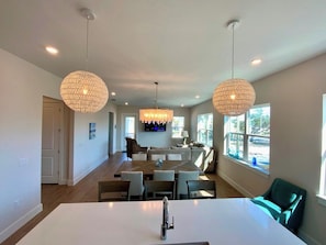 A modern kitchen with a dining area, large windows, and pendant lighting. - Nautical Nest - Quick Walk to Beach (Fort Myers Beach)