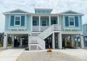 A two-story house with a covered front porch and a staircase leading to the upper level. - Nautical Nest - Quick Walk to Beach (Fort Myers Beach)