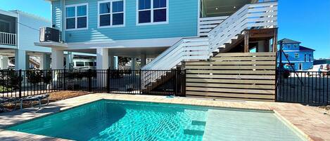 Une maison moderne à deux étages, dotée d’une piscine, d’un patio couvert et d’une cour arrière clôturée.