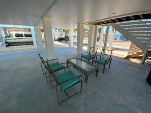 Un patio al aire libre con una mesa de vidrio y cuatro sillas, rodeado de pilares blancos.
