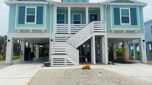 Una casa de dos pisos con una escalera central, un porche cubierto y un camino de entrada.