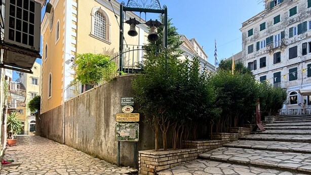 A cobblestone street with a stone staircase leading up to a building with a bell tower.