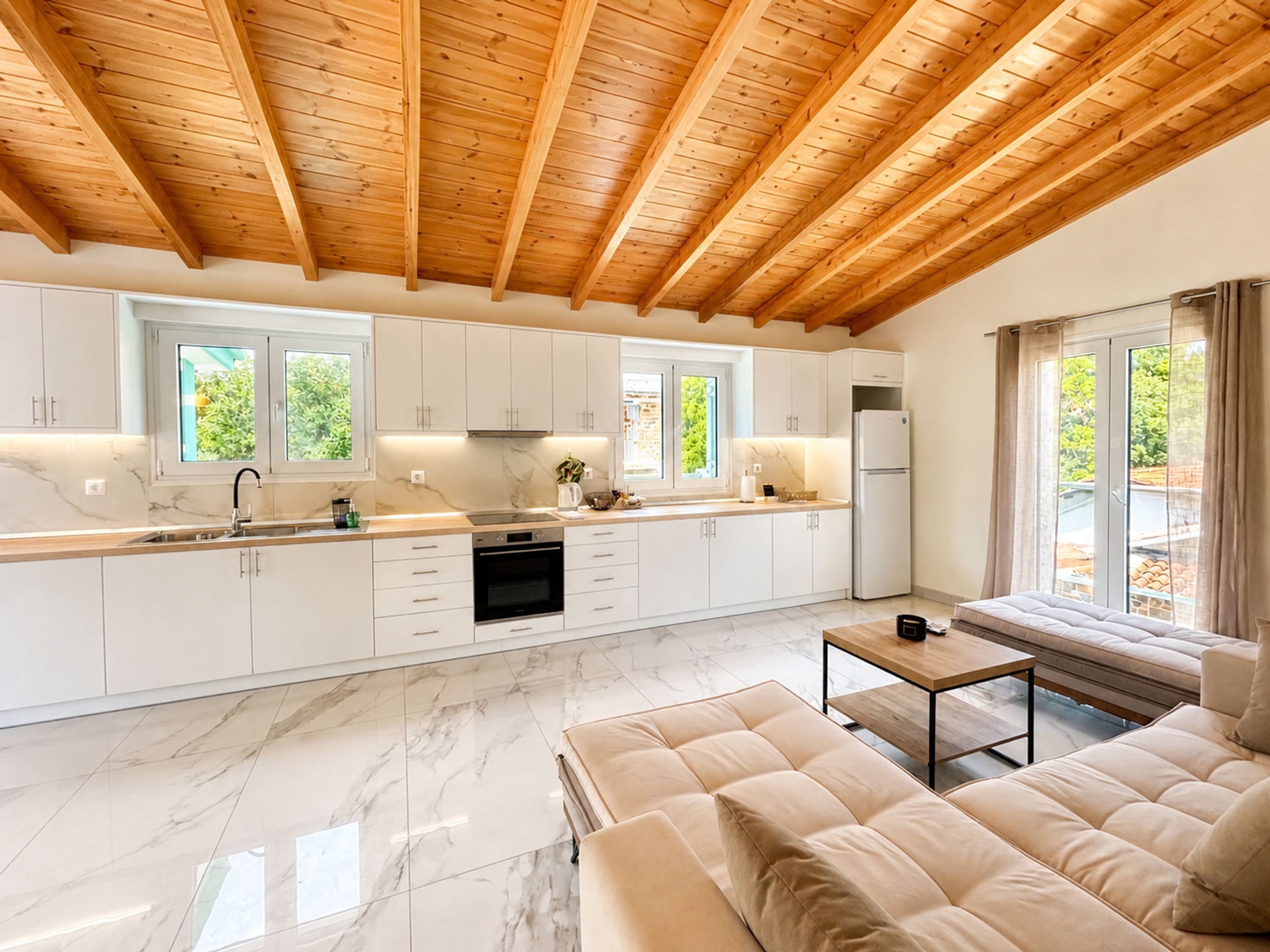 Una cucina moderna con mobili bianchi, un piano di lavoro in marmo e un soffitto in legno.