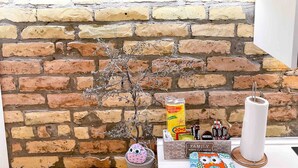 A cozy room with a brick wall, a 'WELCOME' sign, a small tree, a decorative owl, and a Nescafé coffee maker. - Kukuvayia s Nest-centre Old Town Corfu (Corfu)