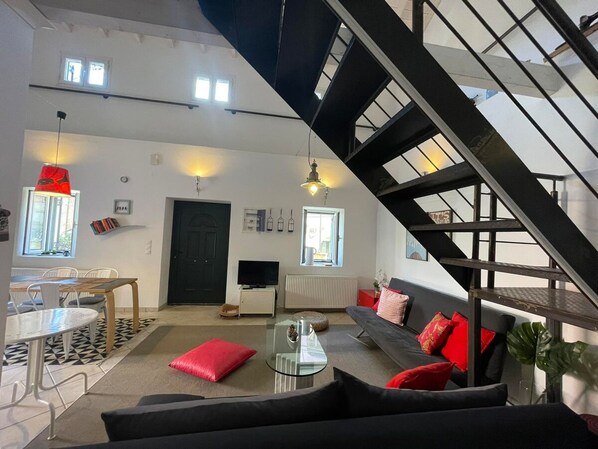 Una sala de estar moderna con una escalera, un comedor y un televisor.