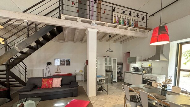 A spacious living area with a staircase, a dining table, and a kitchen. - Ourano -gastouri Village Center (Corfu)