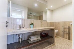 Features a sink, large mirror, and wooden shelf for storage.