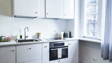 Una cocina moderna con armarios blancos, un lavamanos de acero inoxidable y un horno empotrado.