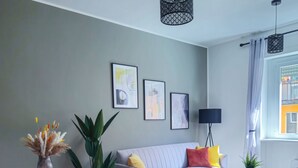 A modern living room with a sofa, orange chairs, a coffee table, and artwork on the wall. - Morgagni Suites (Bologna)