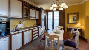 A kitchen with wooden cabinets, a dining table with chairs, and a chandelier. - Rose Corner House (Orvieto)
