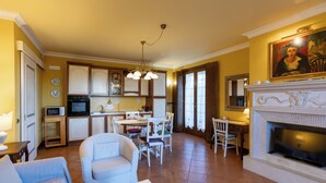 A spacious living area with a fireplace, a dining table, and a kitchen in the background. - Rose Corner House (Orvieto)