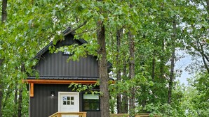 Une cabane dotée d’une terrasse en bois, d’un petit porche et d’une porte.