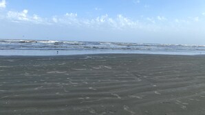 Ein Strand mit Wellen und Fußabdrücken im Sand.