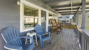 Eine überdachte Veranda mit blauen Adirondack-Stühlen, einem kleinen Tisch und einer Holzbank.
