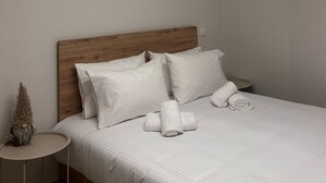 A modern bedroom with a wooden headboard, white bedding, and a unique ceiling light fixture. - Abete Luxury Apartments (Metsovo)