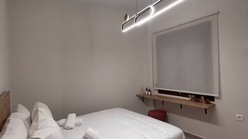 A modern bedroom with a bed, a bedside table, a TV mounted on the wall, and a ceiling light fixture.