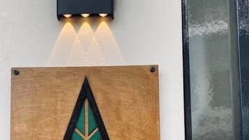 A wooden sign with a leaf design and the text "Abete Luxury Apartments" mounted on a wall.