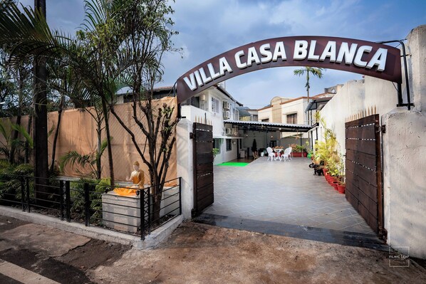 La entrada a Villa Casa Blanca, con un camino de entrada cerrado por una reja y una pequeña estatua al frente.