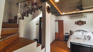 A bedroom with a wooden staircase, a bed with white bedding, a ceiling fan, and a wall-mounted air conditioner. - Have fun with the whole family at this Stylish 4 Bedroom private pool Villa (Lonavala)