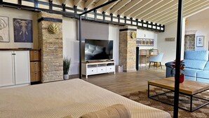 Ein modernes Wohnzimmer mit einer Couch, einem Fernseher und einem Essbereich mit Stühlen.
