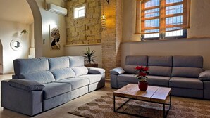 Ein Wohnzimmer mit zwei grauen Sofas, einem Holztisch und einer Steinwand.