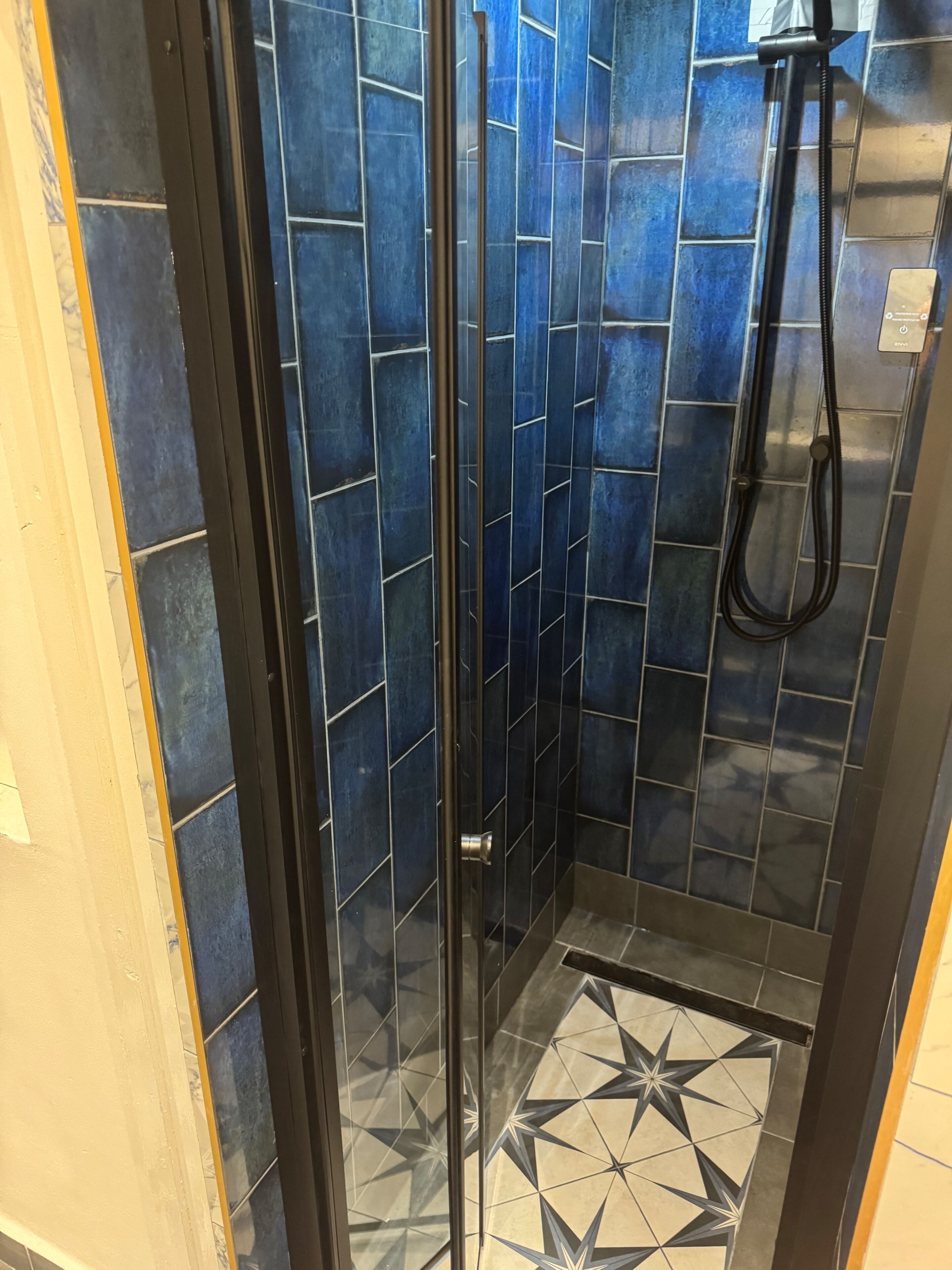A shower with blue tiles and a star-patterned floor.